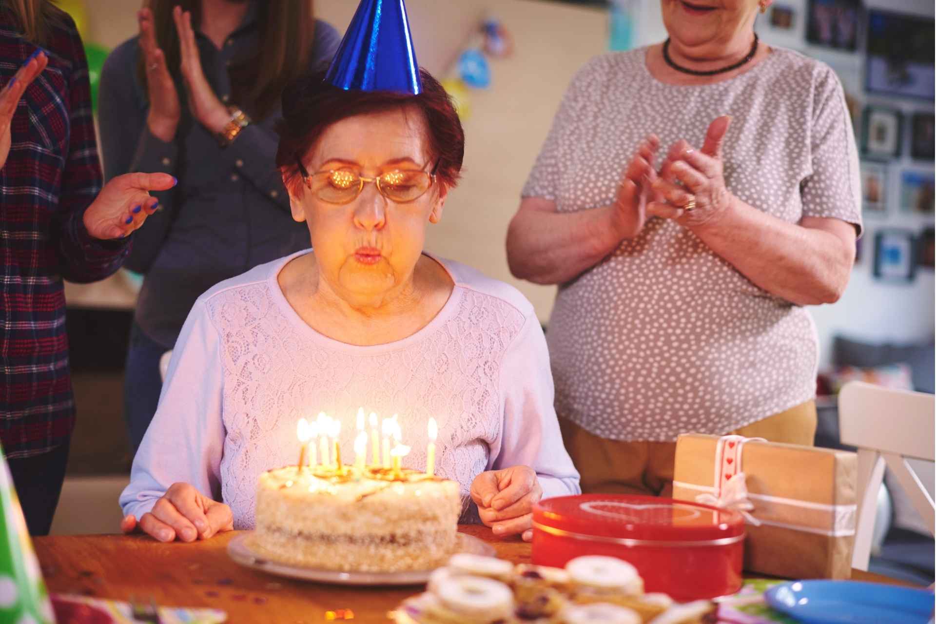 Senior blowing out candles on a birthday cake